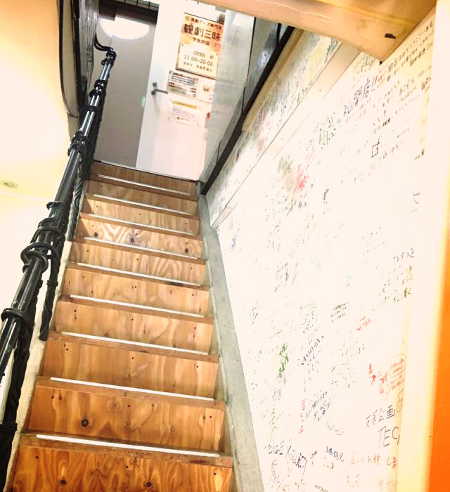カレー屋の左側にある階段から2階へ。階段にはサインがぎっしり。